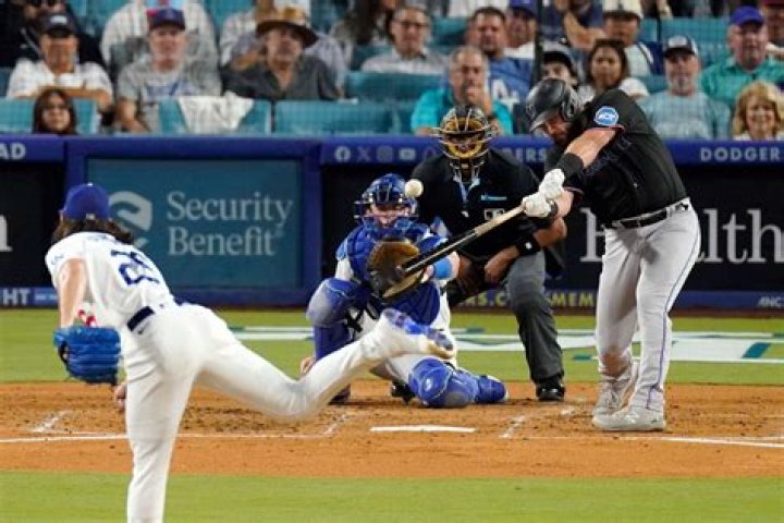 A baseball game with a batter, catcher and umpire on a beautiful sunny