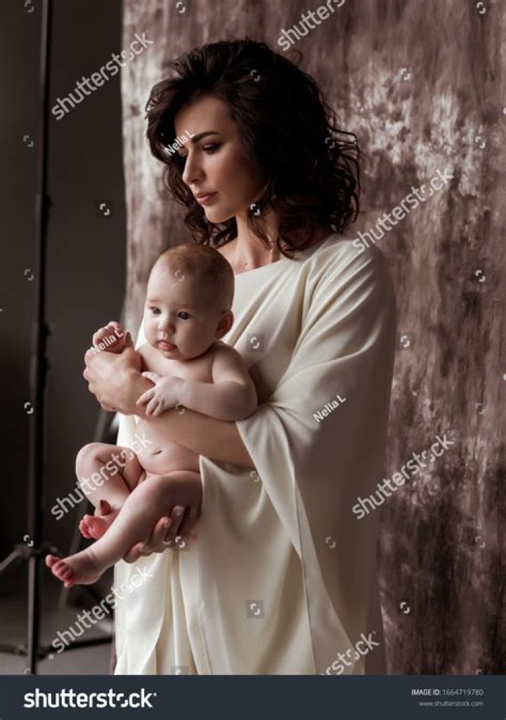 a woman holding a baby in her arms while walking down the street with