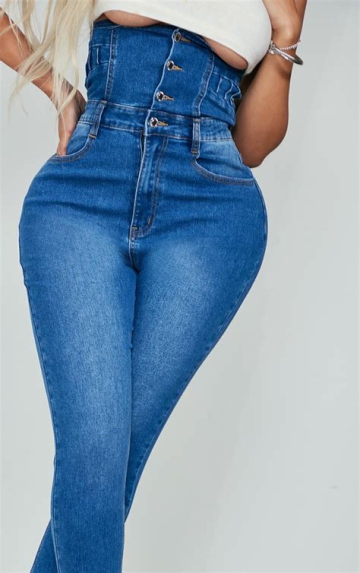 a woman in high waist jeans is smiling and holding a water bottle while