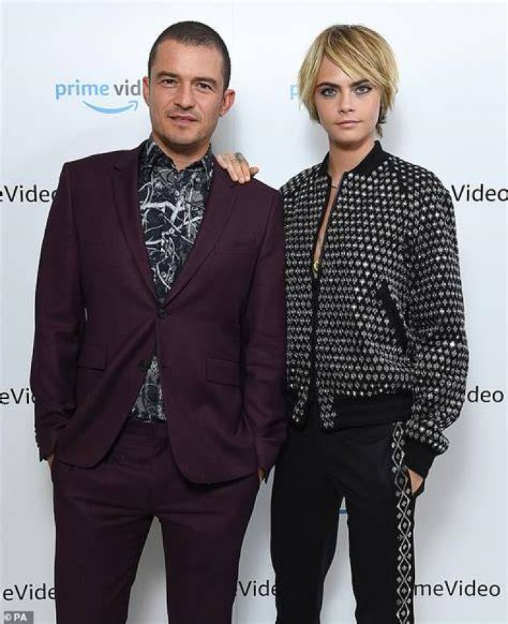 Cara Delevingne bares chest in monochrome suit with Orlando Bloom