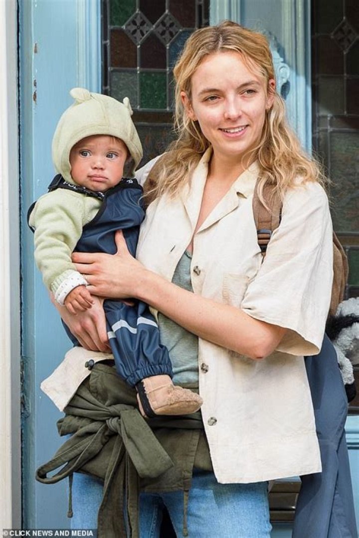 Dishevelled Jodie Comer comforts a baby while filming new dystopian