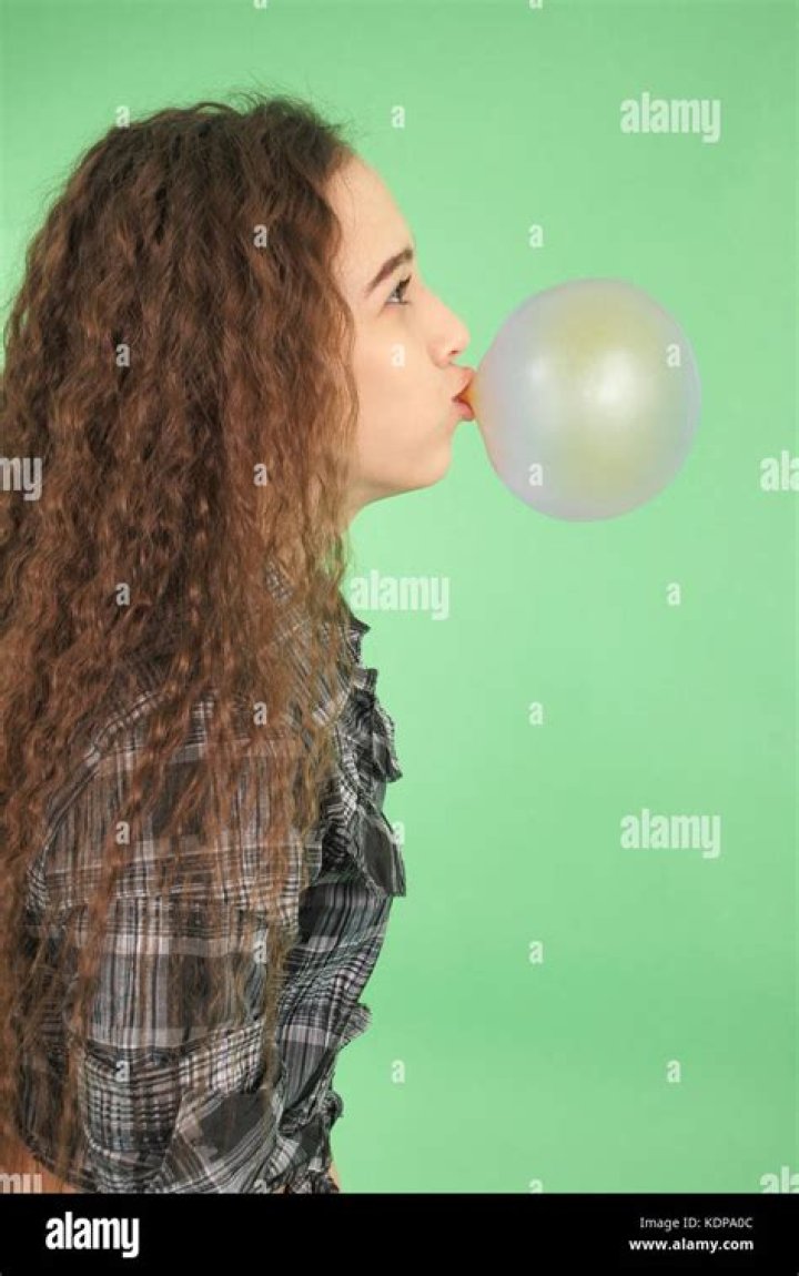 Girl blowing a bubblegum bubble isolated on green Stock Photo Alamy