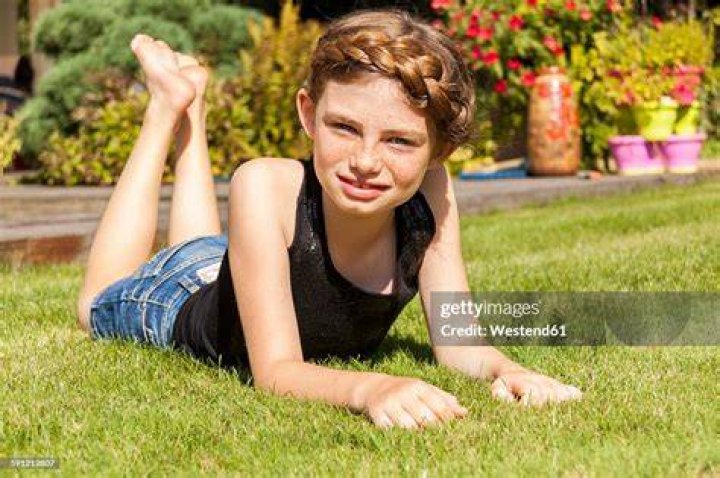 Portrait of girl lying on bed with mothers feet Stock Photo Dissolve