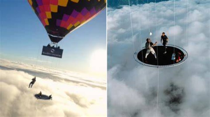 Skydivers jump on trampoline hanging from floating hot air balloon