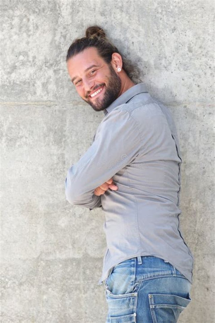 Smiling man leaning against wall Stock Photo Alamy