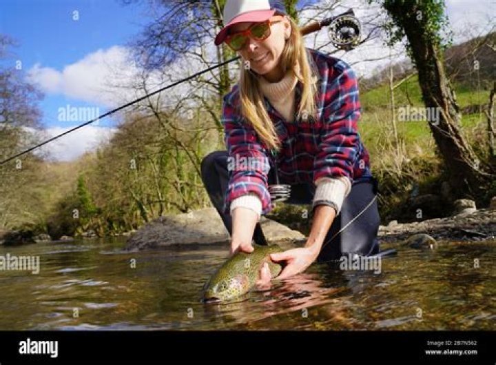 woman catching rainbow trout fly in river Stock Photo Alamy